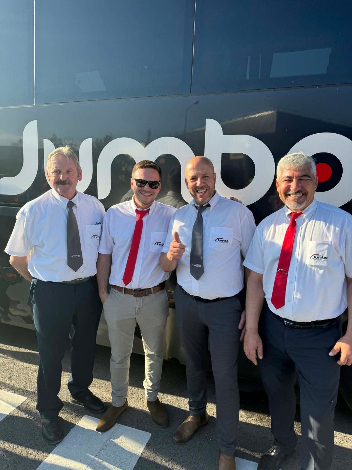 Quatre chauffeurs Jumbo Tourisme devant leur autocar.