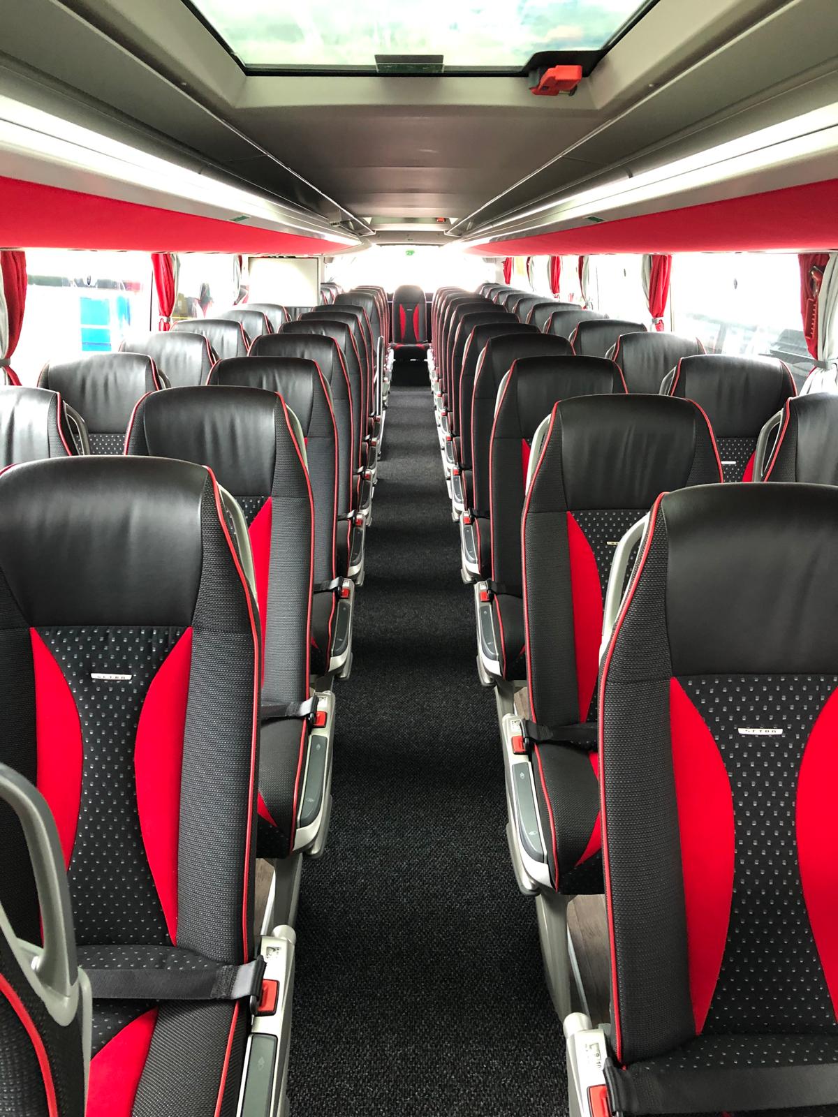 Allée et sièges noir et rouge d’un autocar Jumbo Tourisme.